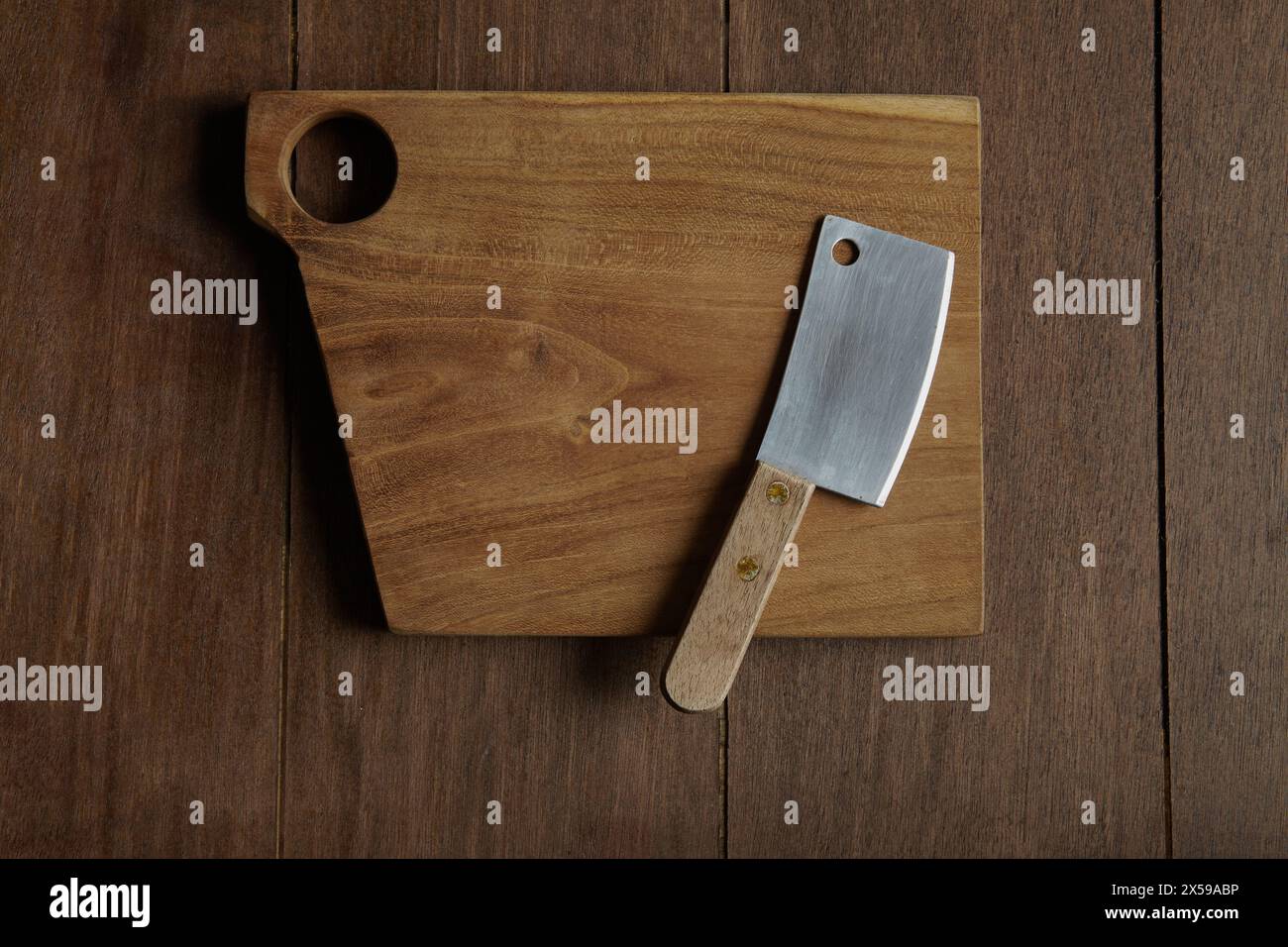 Un piccolo coltello per tagliare la carne su un tagliere di legno con fori Foto Stock