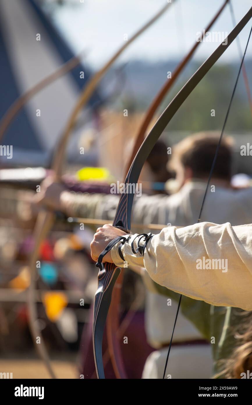 Attrezzatura medievale per il tiro con l'arco, arco e freccia nelle mani di un uomo. Fiera medievale. Foto di alta qualità Foto Stock