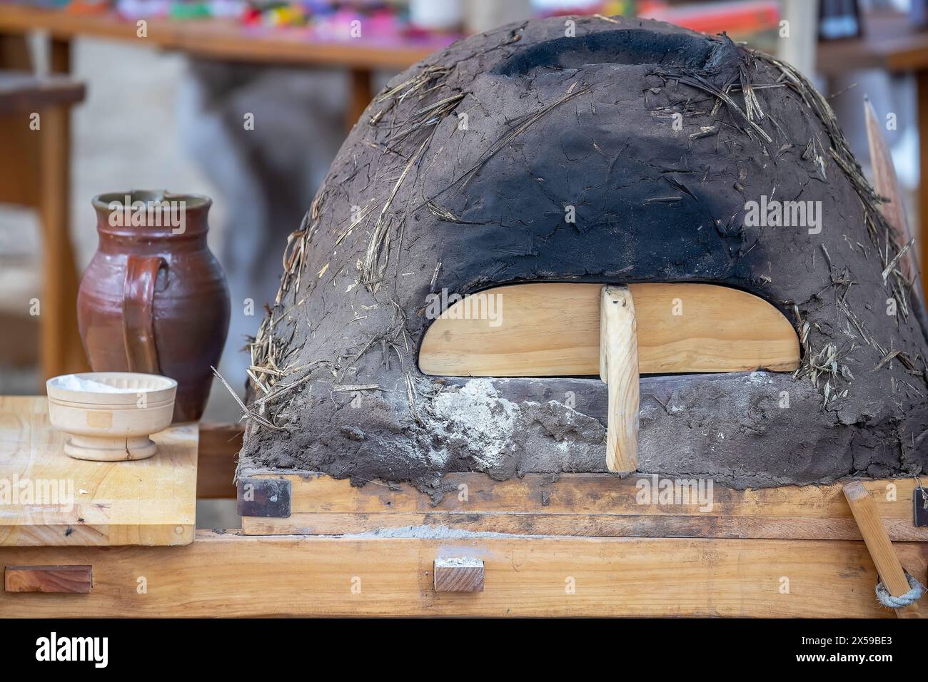 Caraffa in ceramica, ciotola con farina e forno in argilla medievale per cuocere il pane da vicino, piatti su un tavolo di legno, stile di vita medievale, natura morta. Foto Stock