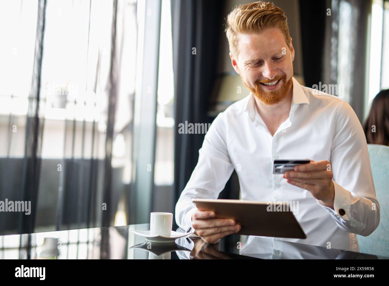 Uomo d'affari di successo che possiede una carta di credito, usando un tablet digitale. Concetto di shopping online Foto Stock