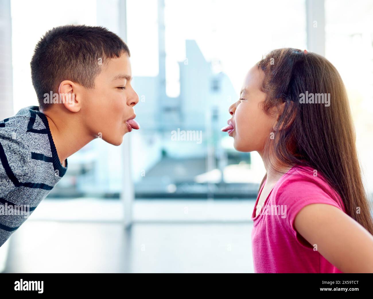 Bambini, combattere o stupidi con la lingua fuori, problemi o frustrati con i giovani a casa in salotto. Giovani, litigi o conflitti in casa, appartamento o. Foto Stock