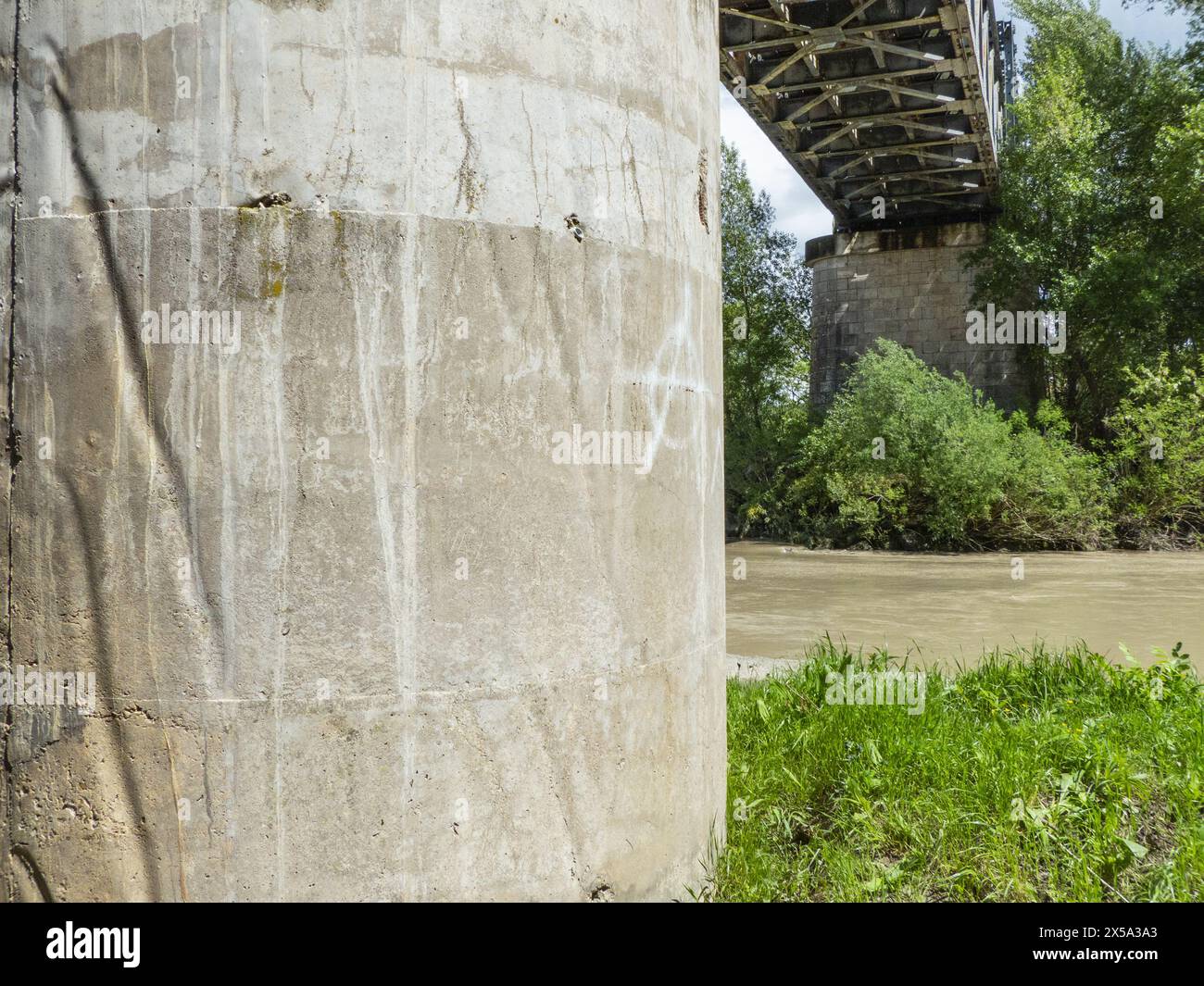 Dettaglio di un pilone in cemento che sostiene un ponte ferroviario sul fiume Foto Stock