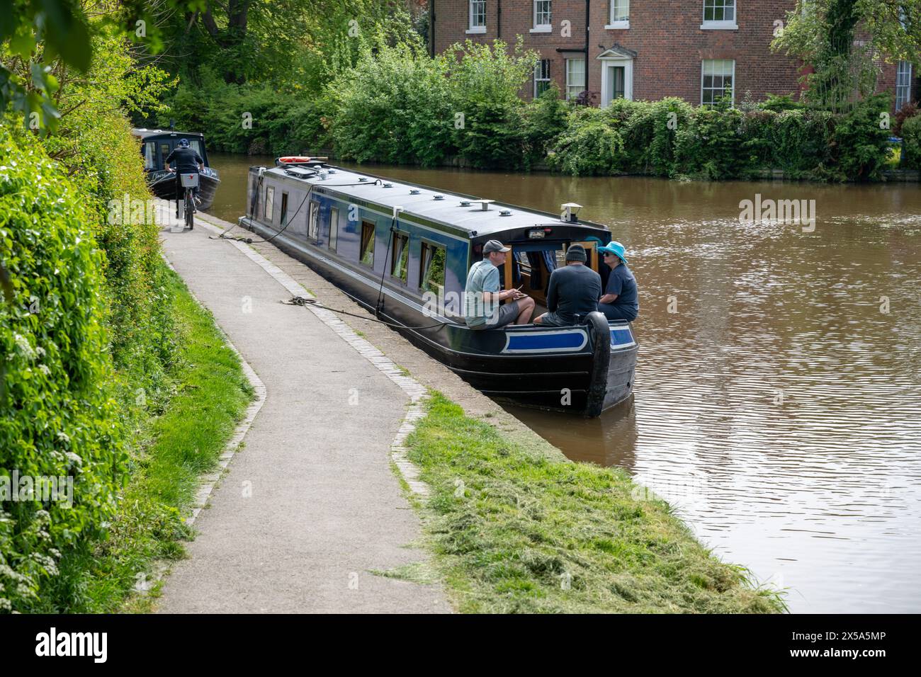 Tre uomini si siedono sulla prua della loro barca noleggiata ormeggiata sul canale Llangollen a Ellesmere, nello Shropshire, mangiando e bevendo. Foto Stock