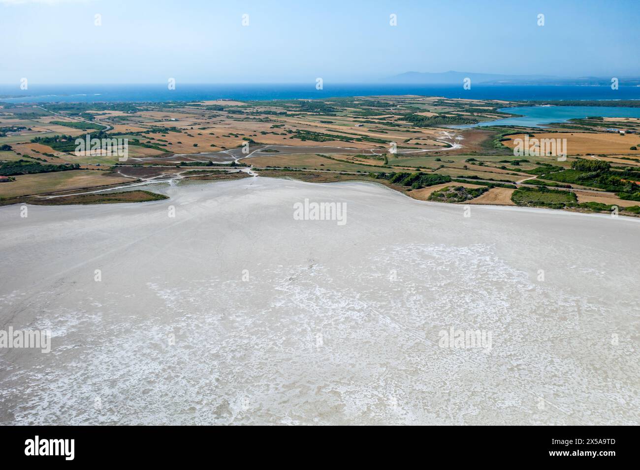 Una splendida ripresa aerea cattura la bellezza delle saline sarde con vista sul paesaggio lussureggiante e sul mare lontano Foto Stock