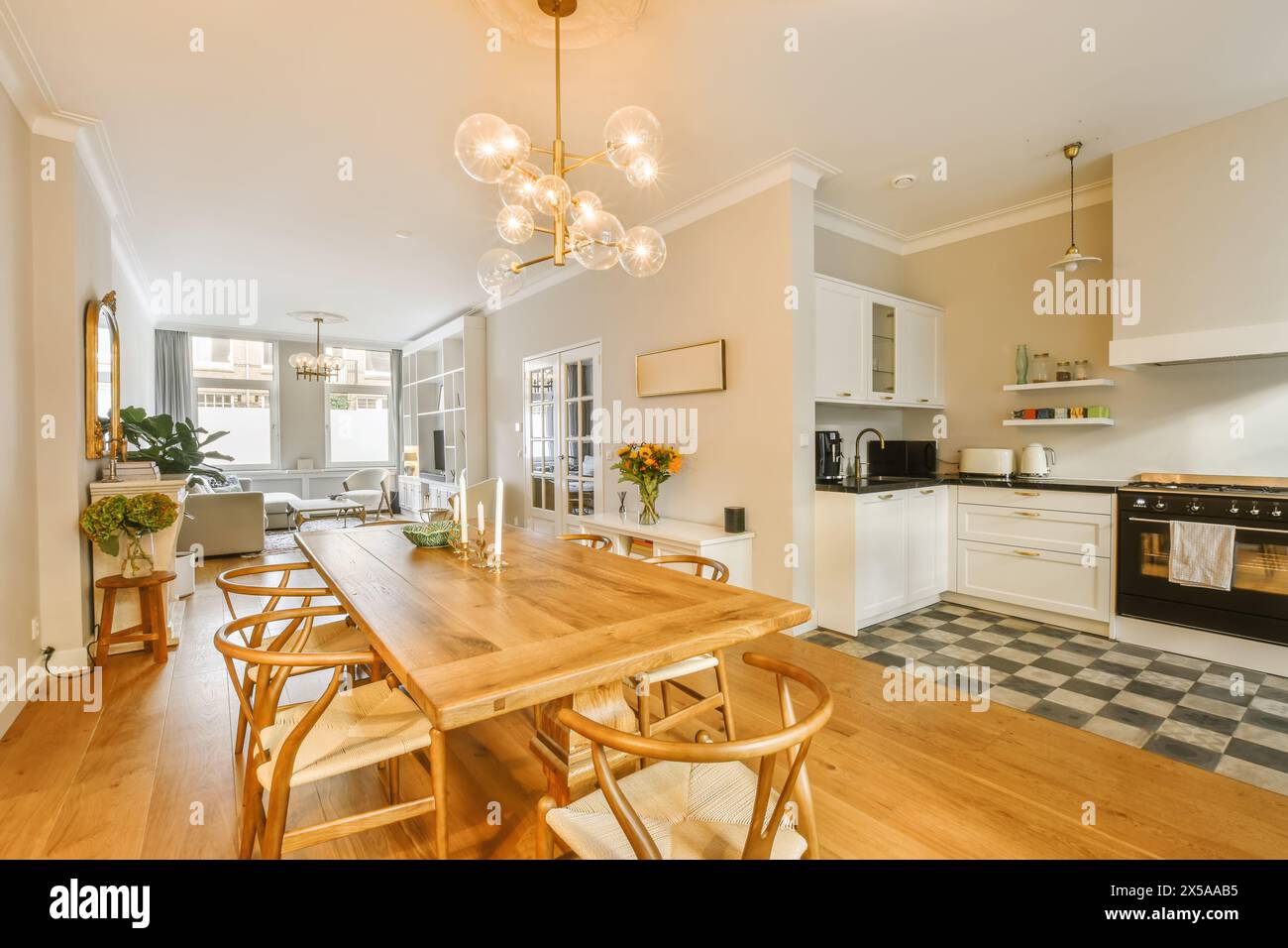 Un'invitante cucina open space e zona pranzo con tavolo da pranzo in legno, illuminazione moderna e interni accoglienti. Foto Stock