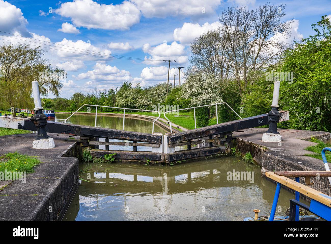 Grand Union Canal Main Line, Calcutt Locks, Inghilterra: Un motoscafo nella serratura superiore con i cancelli chiusi in una luminosa giornata estiva contro un cielo blu Foto Stock
