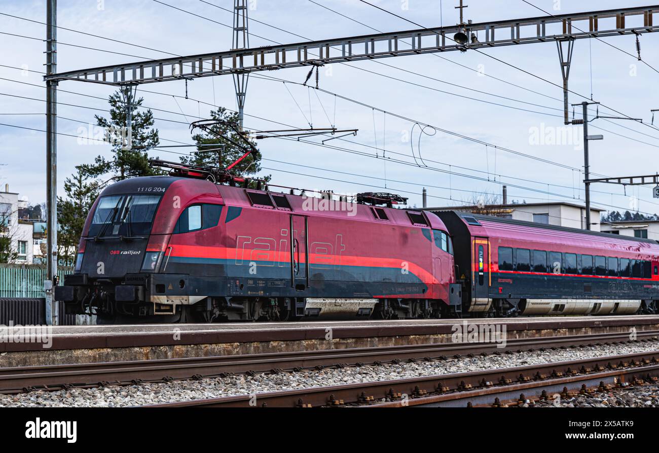 Der ÖBB Railjet ist aus Wien unterwegs an den Hauptbahnhof Zürich. Gezogen wird der Personenzug von einer Taurus Lokomotive. Der Zug fährt beim Bahnho Foto Stock