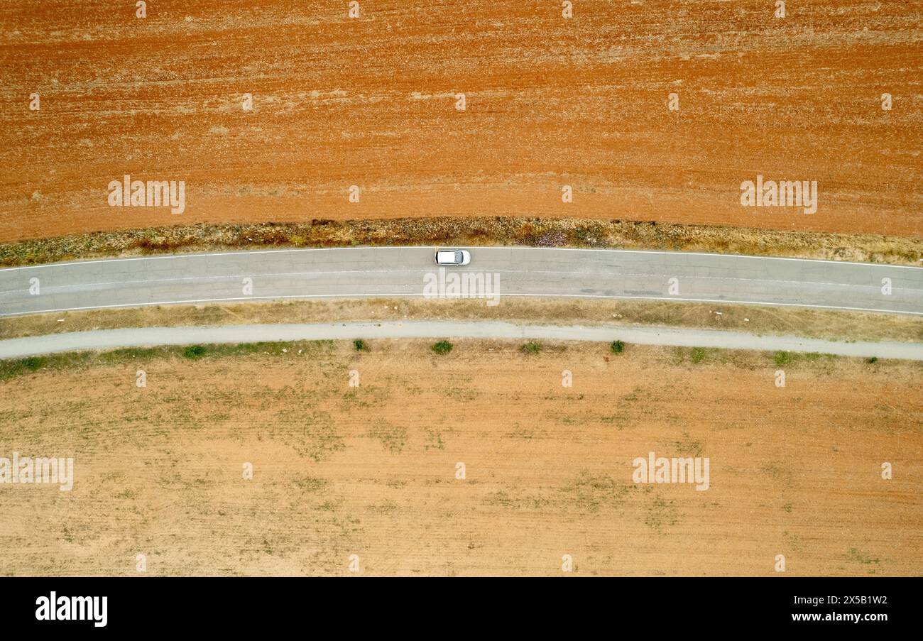 Volo con droni di campagna su strada rurale vuota con guida in auto. Terreno asciutto Foto Stock