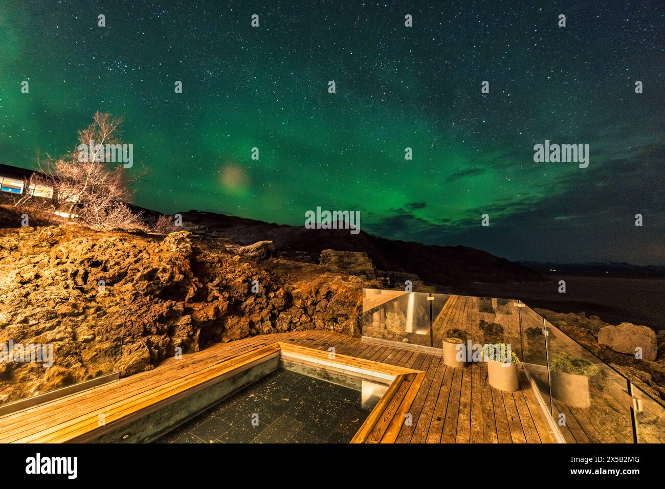 La splendida aurora boreale, l'aurora boreale si affaccia sulla piscina termale calda in un hotel di lusso di notte Foto Stock