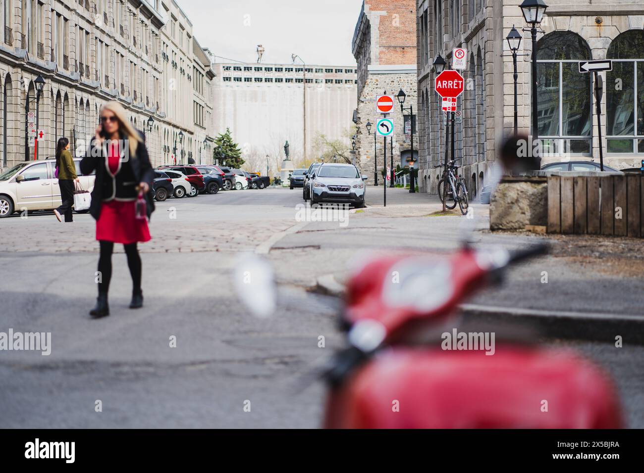 Donna che cammina accanto alla Vespa Rossa nel cuore del Porto Vecchio di Montreal, Canada, Quebec Foto Stock