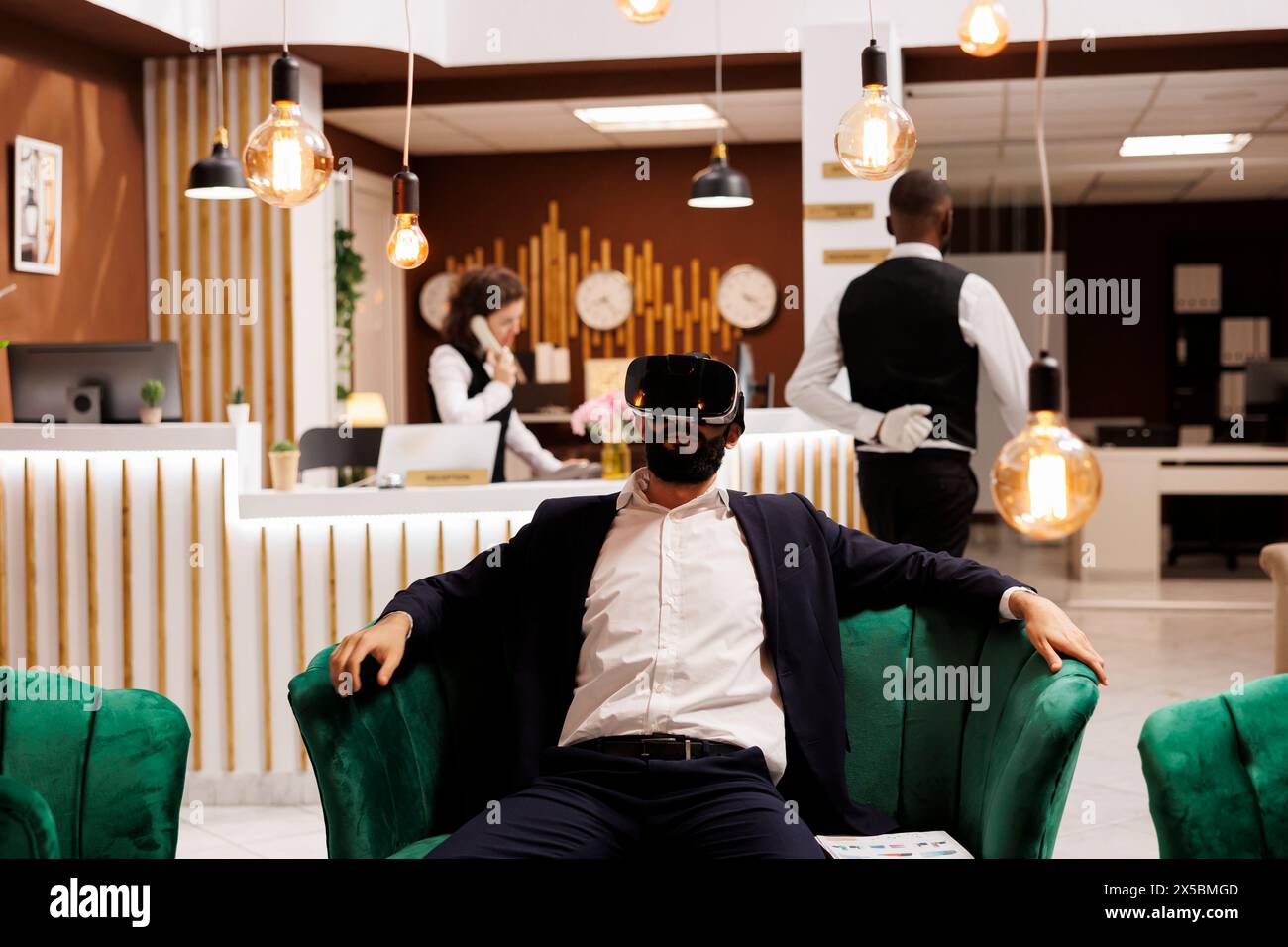 L'uomo d'affari lavora con il visore vr nella hall dell'hotel, utilizzando nuovi occhiali 3d per la visione interattiva prima di effettuare il check-in. Giovane adulto con tecnologia di realtà virtuale in viaggio di lavoro. Foto Stock