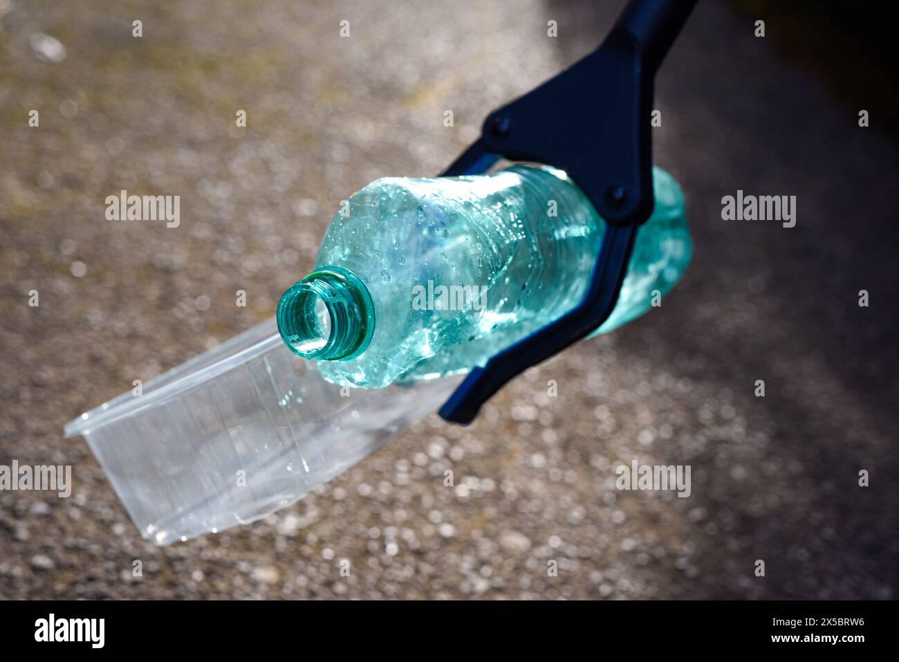 Raccogliere i rifiuti di plastica e i rifiuti che sono caduti sul marciapiede per pulire e curare l'ambiente Foto Stock