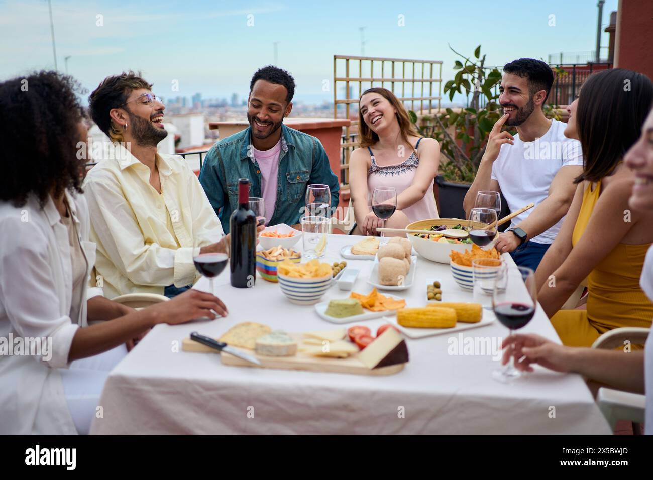 Gruppo di giovani che ridono gustando il pranzo insieme all'aperto Foto Stock