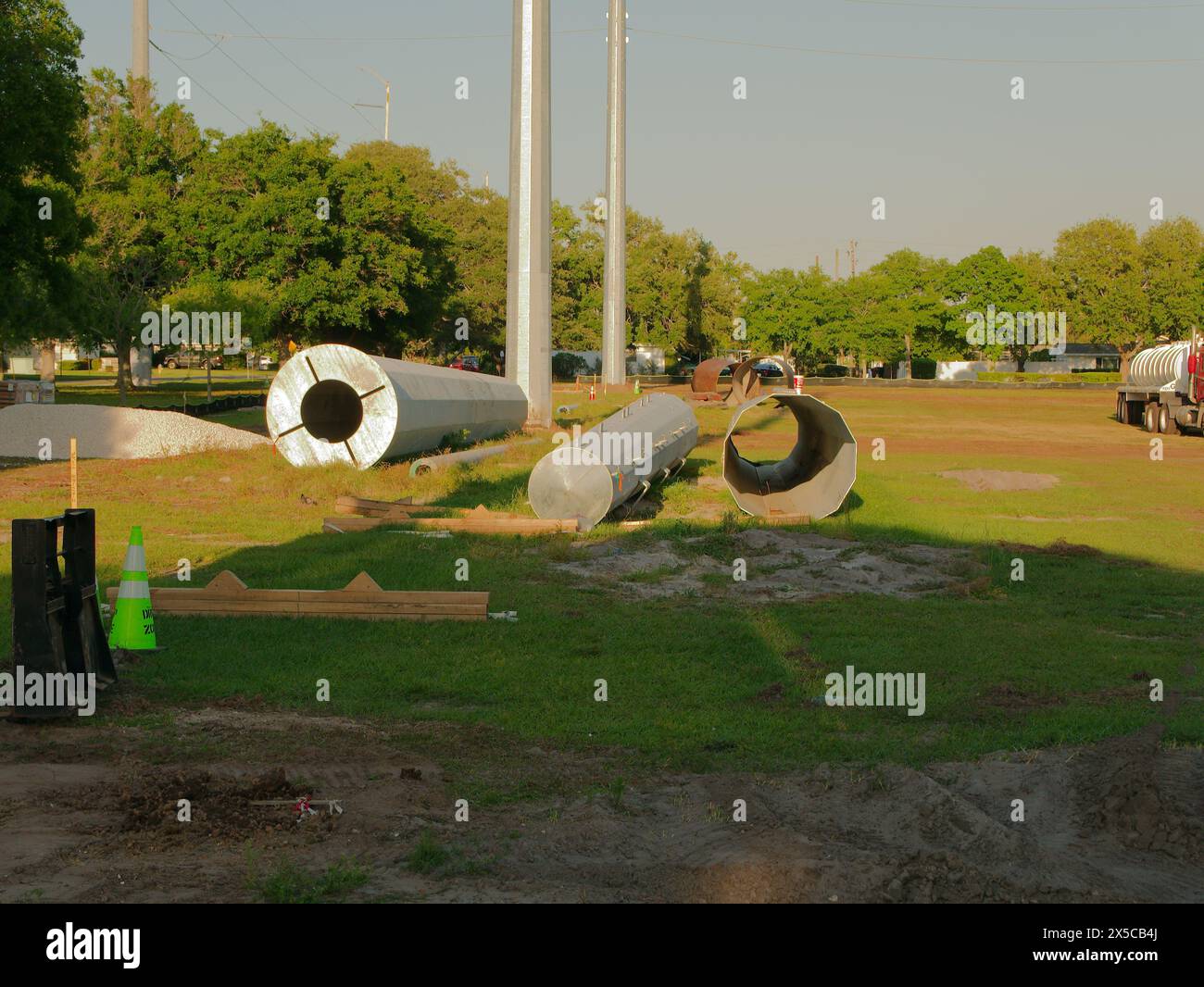 Ampia visuale sull'erba verde sezione di più poli in acciaio per la posa di terreno e di un autocarro e sottostazione elettrica sul retro. Nel tardo pomeriggio. Cielo blu Foto Stock