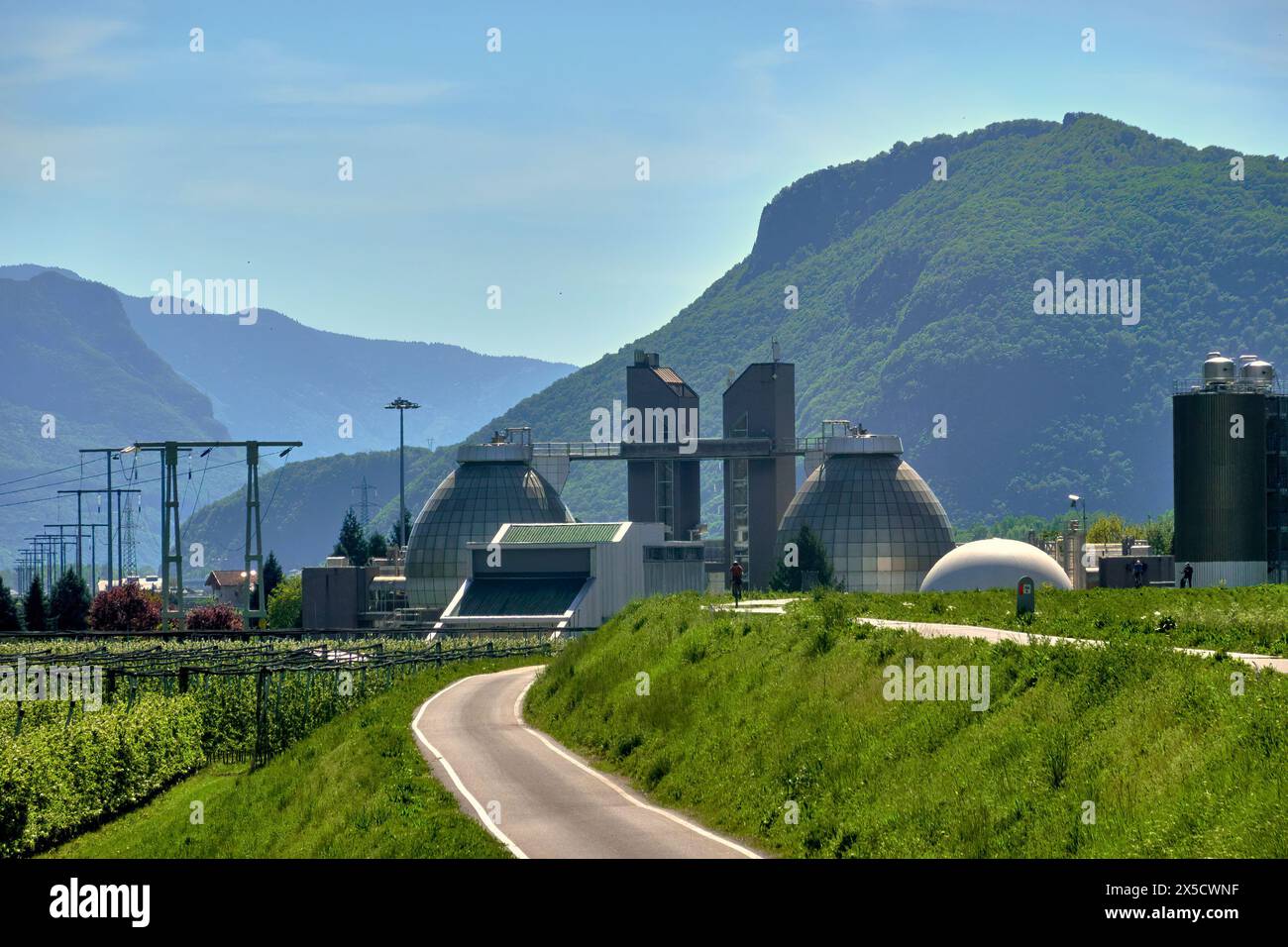 Bolzano, Italia, 13 aprile 2024: Grande impianto di depurazione con torri di digestione scintillanti sulla pista ciclabile di via Claudia Augusta in Italia Foto Stock