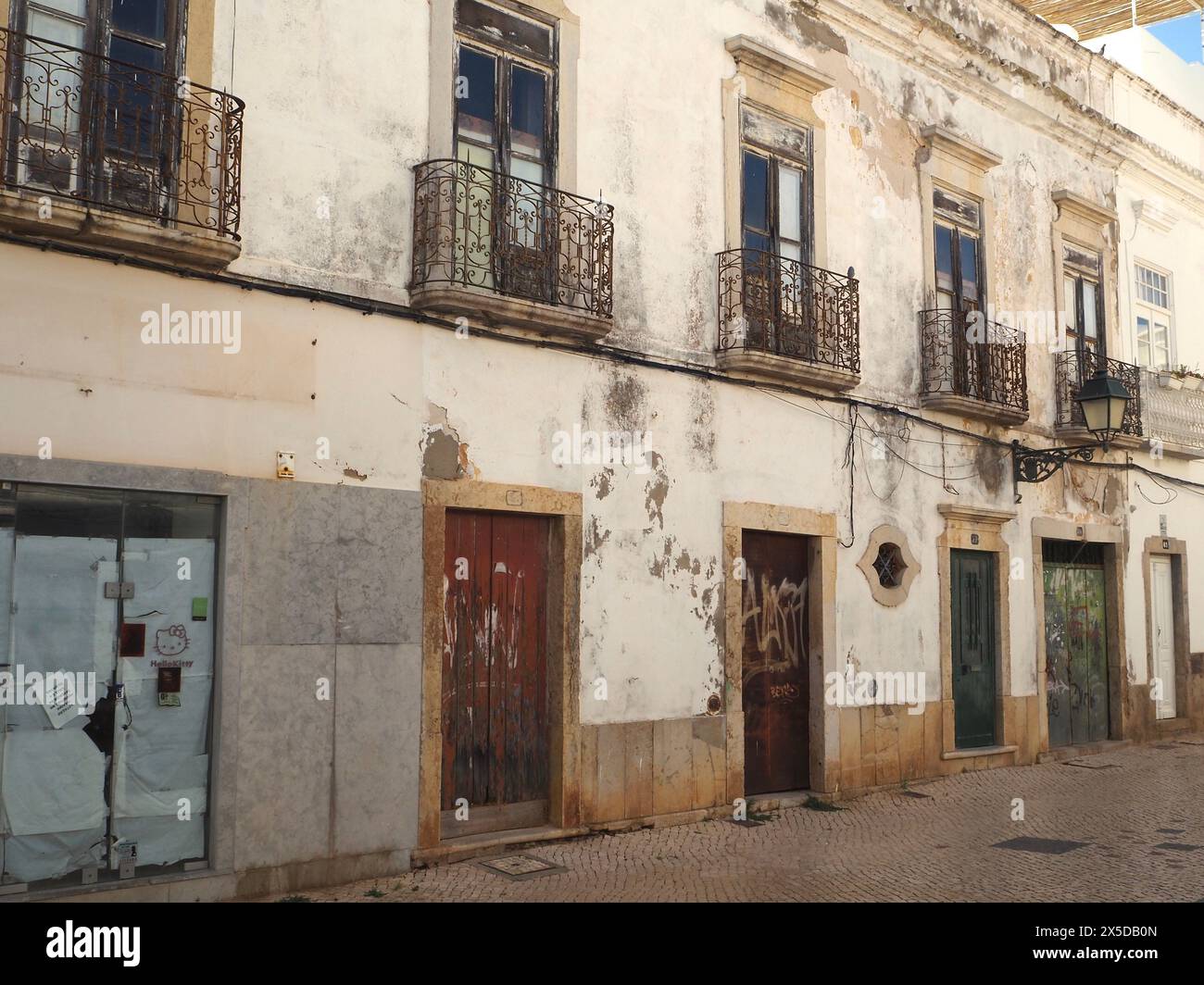 Vecchie case in pietra portoghesi semi abbandonate con balconi Giulietta che necessitano di rinnovo o rinnovo. Rua Vasco da Gama, Olhão, Algarve, Portogallo Foto Stock