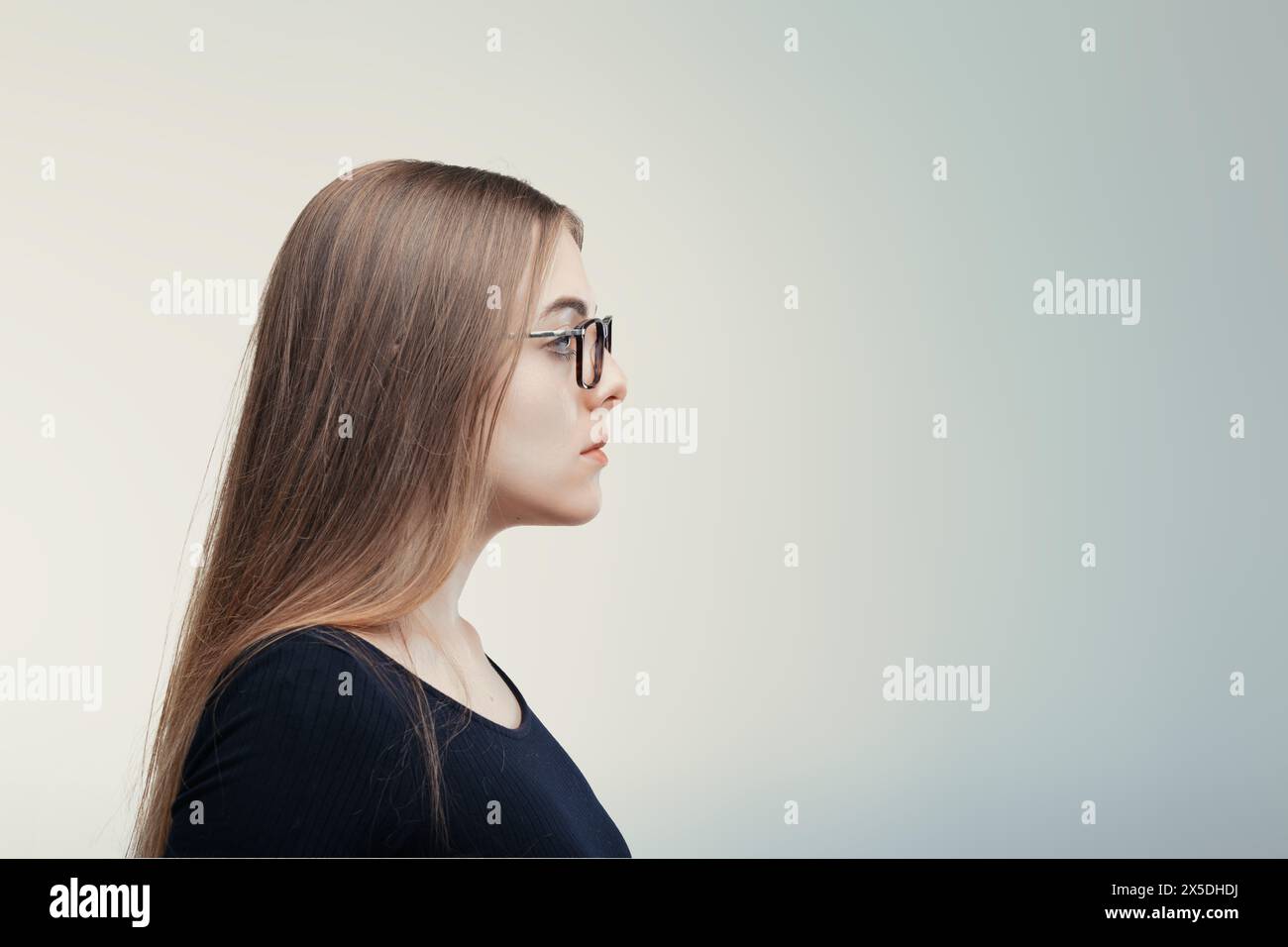 Ritratto laterale di una giovane donna contemplativa, la sua espressione serena e concentrata verso l'esterno Foto Stock