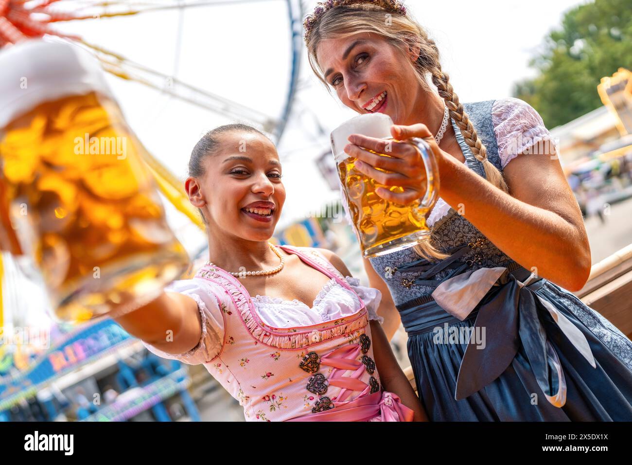 Due donne in abiti tradizionali tracht brindano gioiosamente tazze da birra all'oktoberfest o al Duld in germania Foto Stock