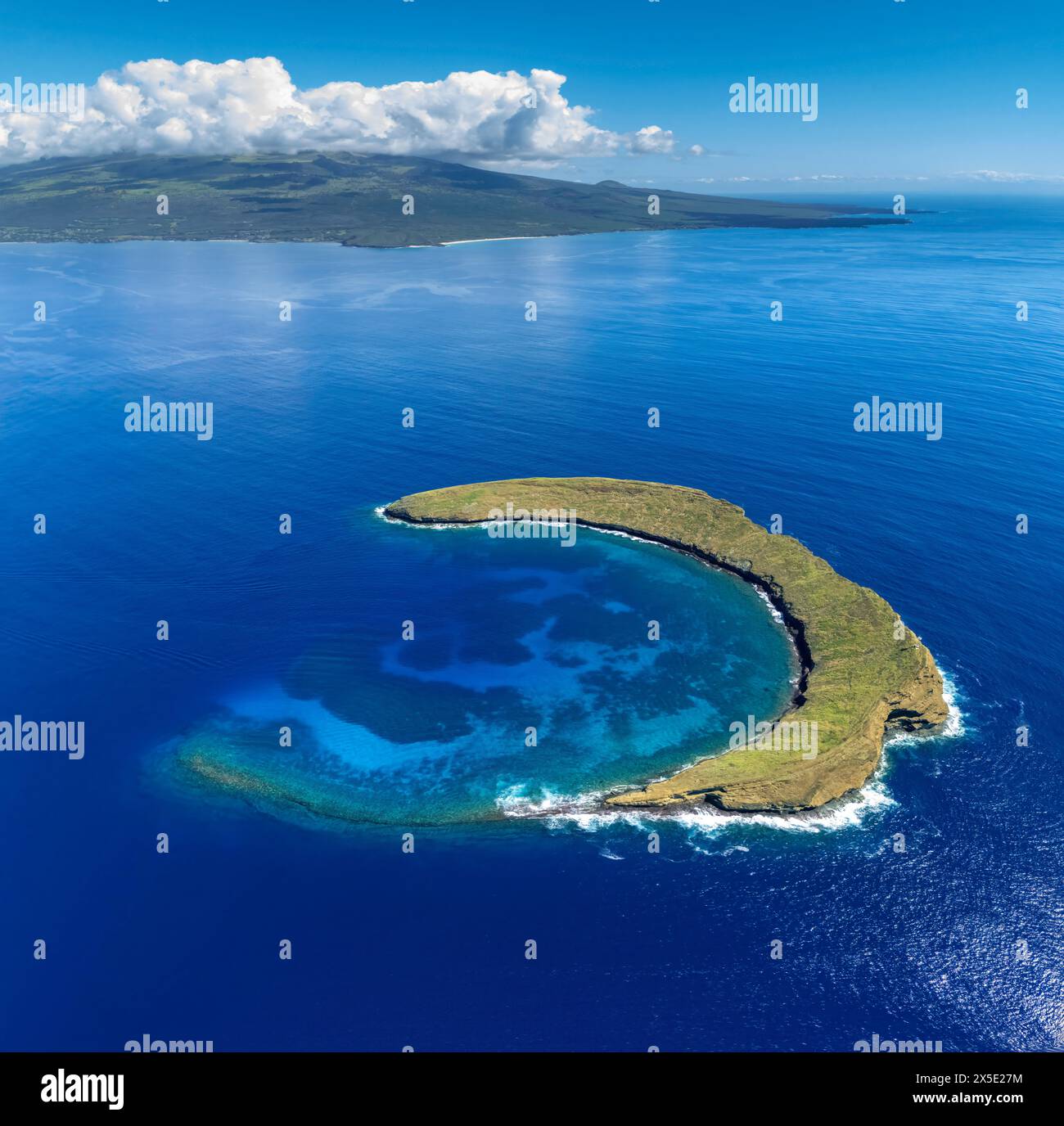 Cratere Molokini, ripresa aerea dell'intera isoletta a forma di mezzaluna con l'isola di Maui sullo sfondo, Hawaii. Foto Stock