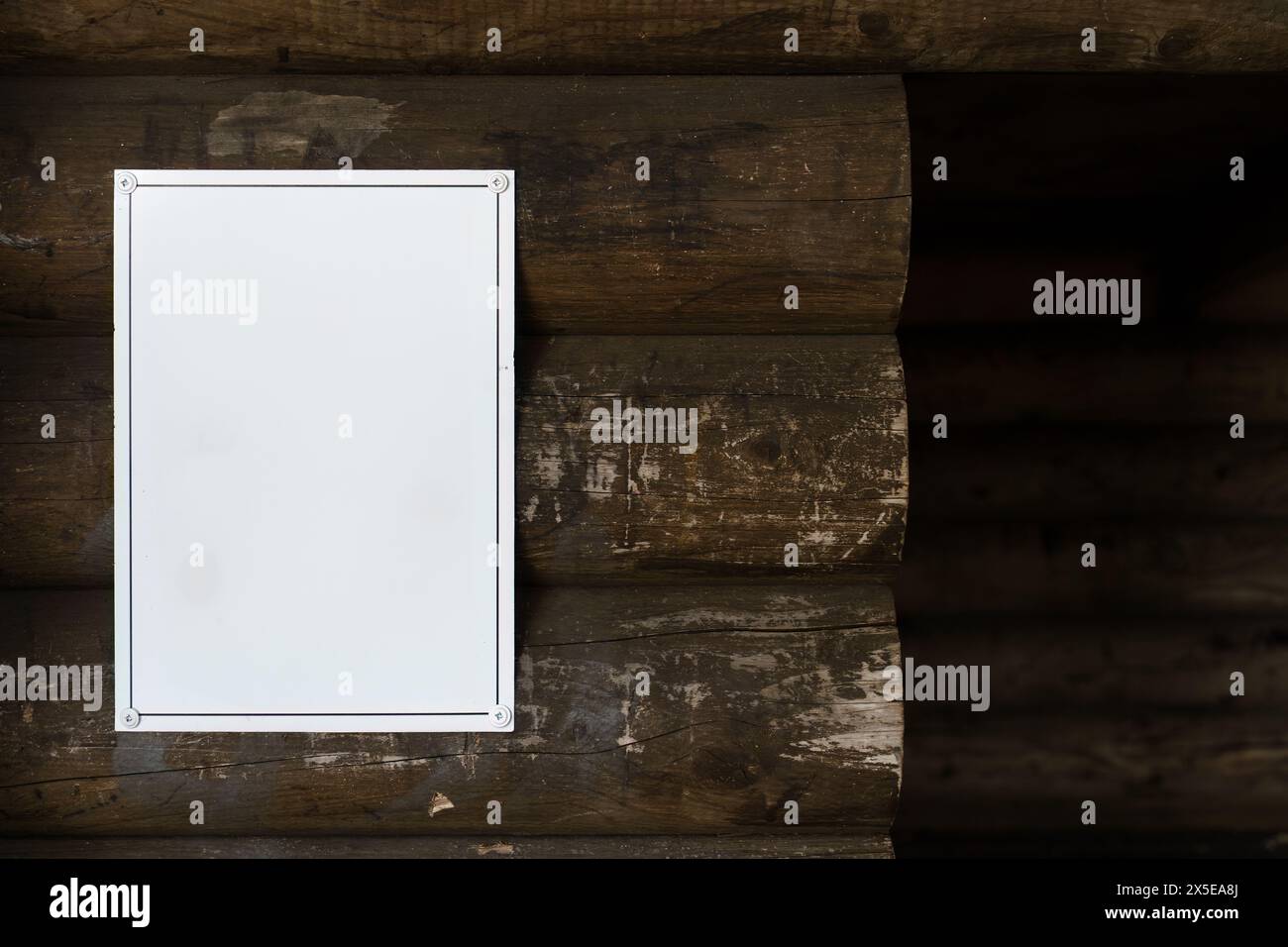 insegna bianca vuota montata sulla parete esterna di un legno di legno di legno di legno di legno di legno di copertura nel bosco. Foto Stock