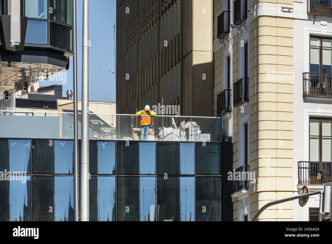 Un operaio edile appoggiato su una ringhiera di un edificio in costruzione Foto Stock