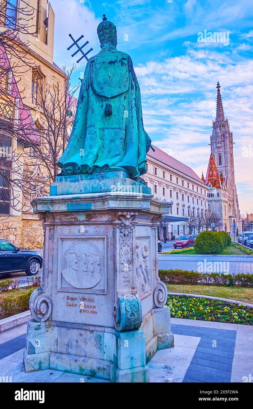 Il monumento in bronzo di Papa Innocenzo XI in piazza Hess Andras contro il campanile gotico della chiesa di Mattia, Budapest, Ungheria Foto Stock