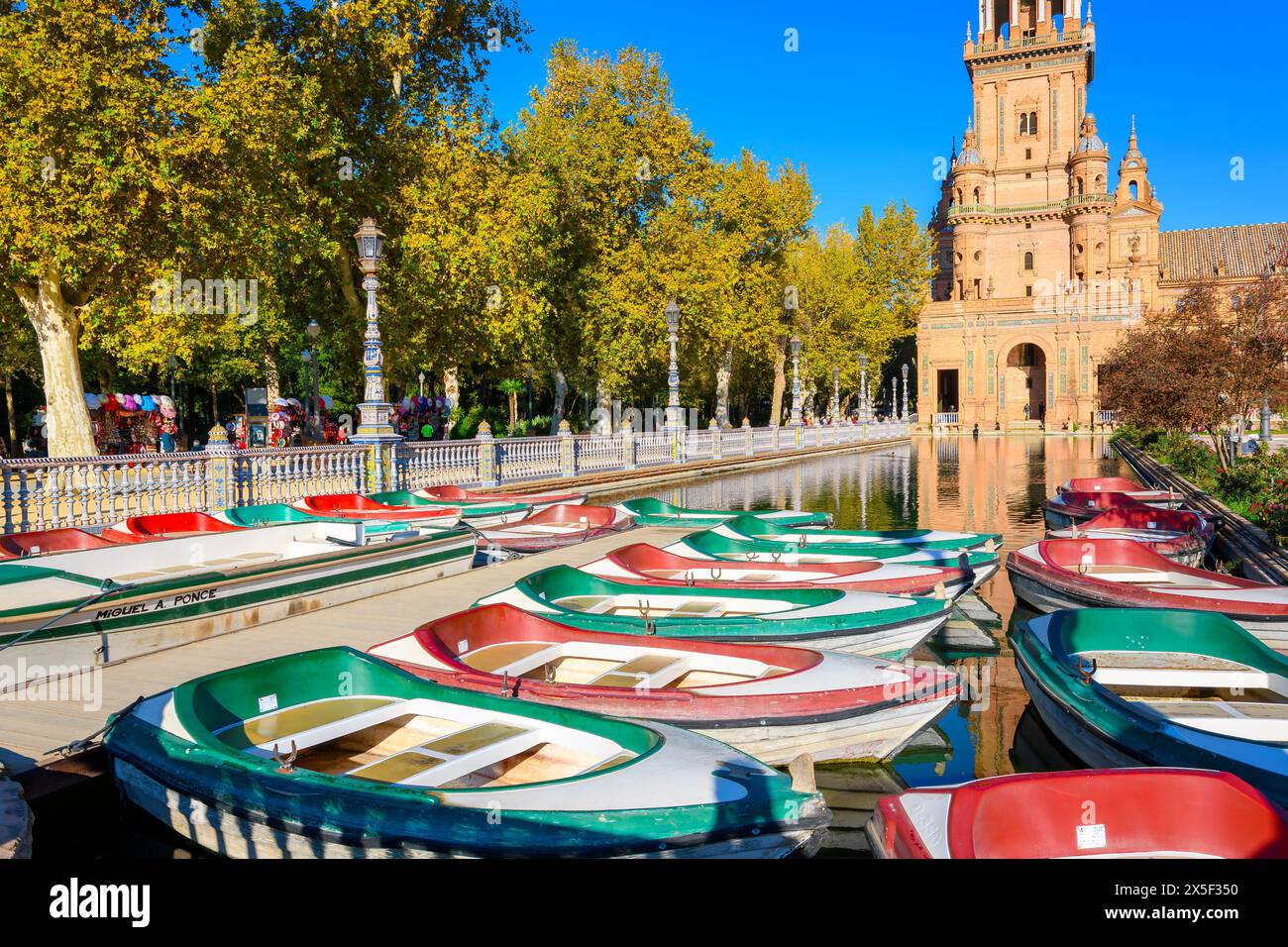 Barche verdi e rosse a noleggio siedono in acqua pronte per i visitatori al mattino presso la piazza pubblica e il parco di Plaza de Espana a Siviglia in Spagna. Foto Stock