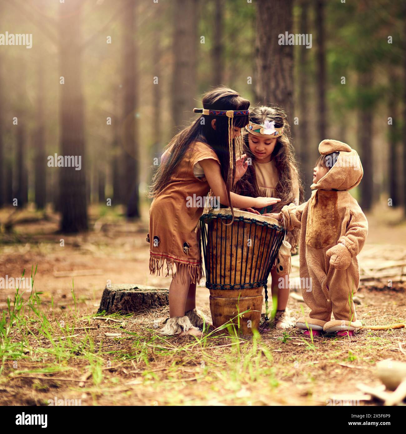 Bambini nativi americani, batteria e musica in natura con giocare, legare e connettersi nei boschi. Fratelli, bambini e strumenti con cultura Foto Stock