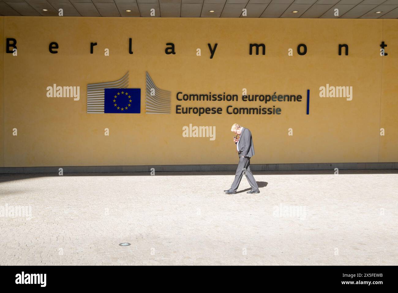 Vecchio che cammina davanti all'edificio Berlaymont, sede della commissione europea. Un edificio per uffici a Bruxelles, Belgio. Foto Stock