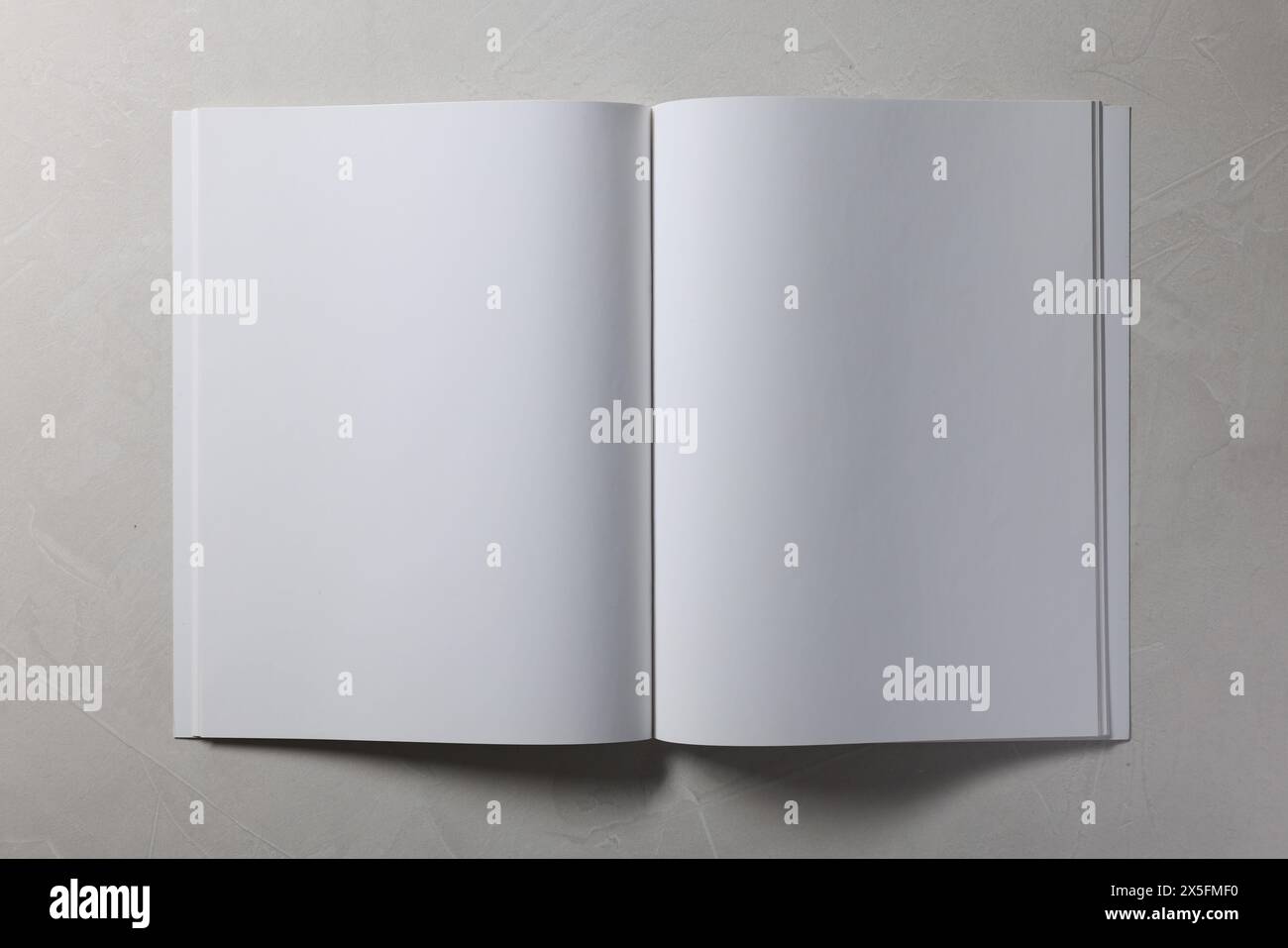 Aprire il notebook con pagine vuote su sfondo grigio testurizzato, vista dall'alto. Mockup per il design Foto Stock