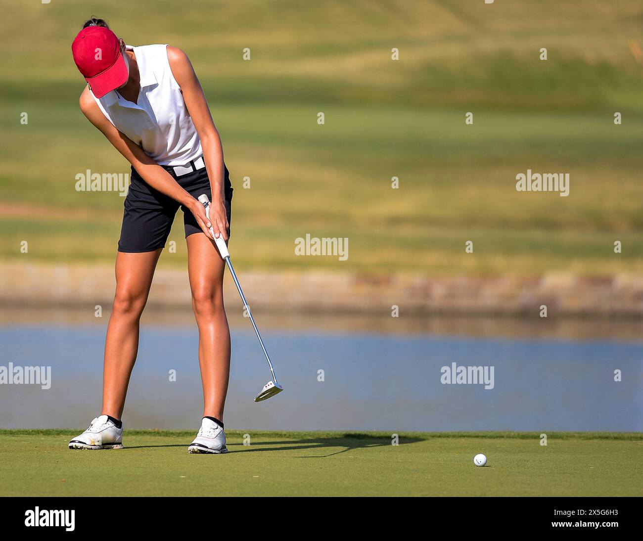 Una giovane golfista che fa un putt su un campo da golf Foto Stock