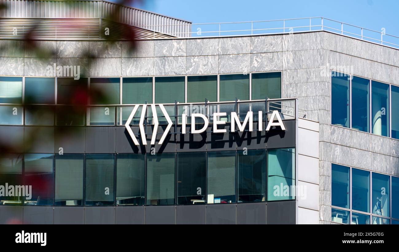 Firma e logo sull'edificio della sede centrale di Idemia, società francese di sicurezza digitale specializzata in biometria, autenticazione dell'identificazione e IA Foto Stock