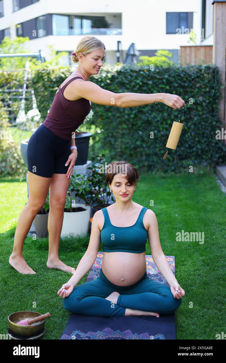 Donna incinta che fa yoga con personal trainer Foto Stock