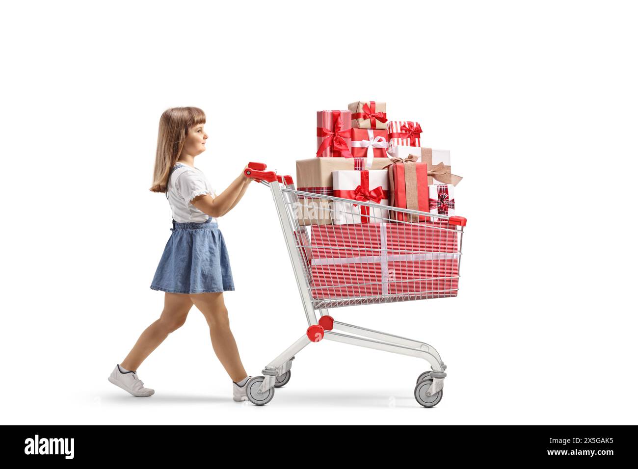 Bambina che cammina e spinge un carrello con scatole regalo isolate su sfondo bianco Foto Stock