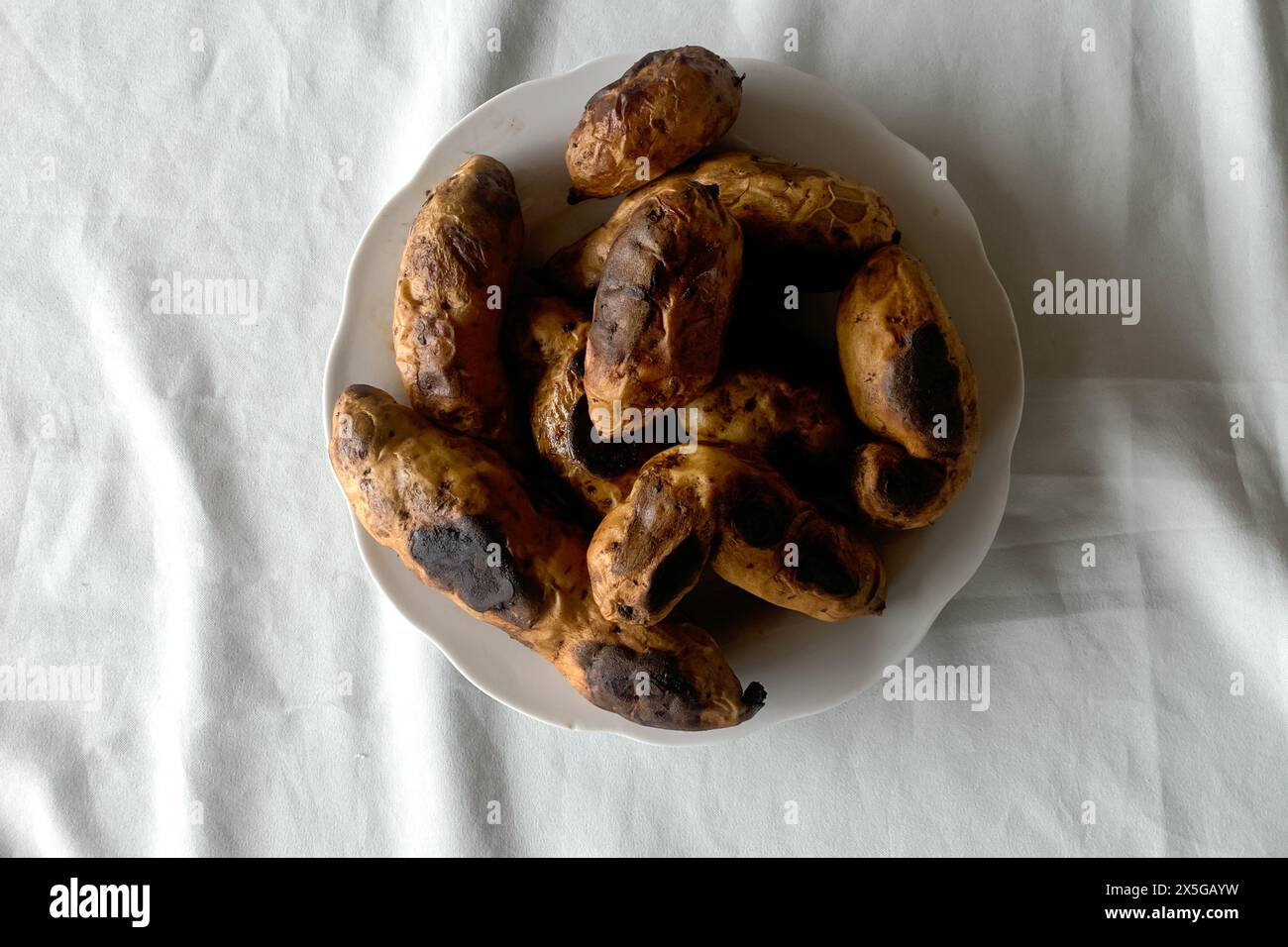 Patata dolce bruciata su sfondo bianco. Foto Stock