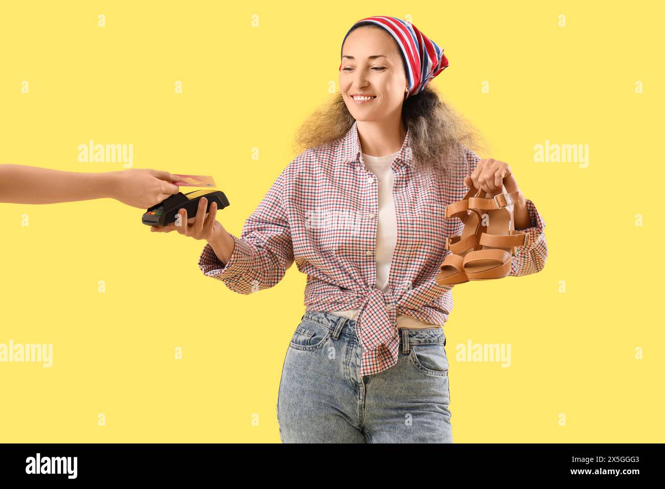 Calzolaio donna che accetta il pagamento per le scarpe riparate su sfondo giallo Foto Stock