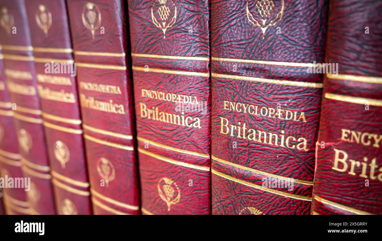 Vista ravvicinata di una fila di volumi dell'Encyclopedia Britannica, libri di riferimento rilegati in pelle rossa in rilievo con testo dorato in una biblioteca Foto Stock