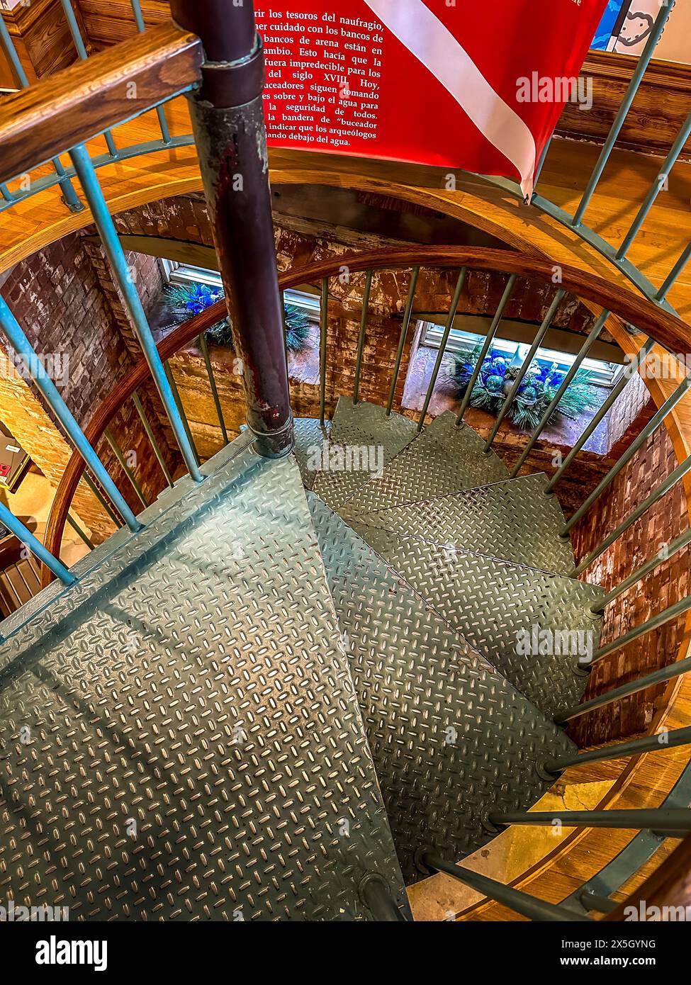 Vista dall'alto di una scala a chiocciola metallica con pareti in mattoni a vista e una bandiera per immersioni in una storica attrazione di St. Augustine, Florida Foto Stock