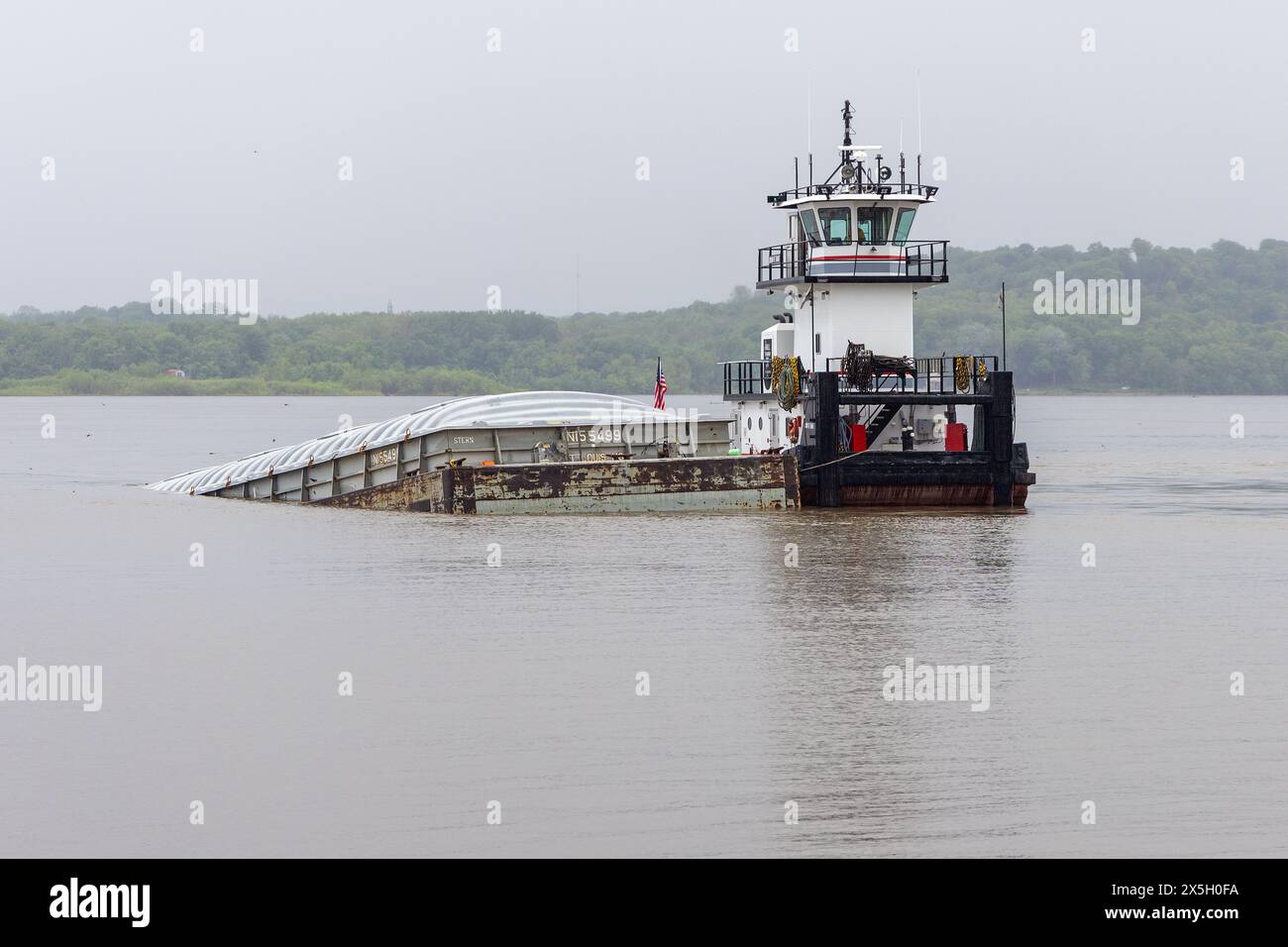 Fort Madison, Iowa, Stati Uniti. 9 maggio 2024. Il rimorchiatore del fiume Don F. Rae tende ad affondare una chiatta che ha colpito accidentalmente il BNSF Santa Fe Swing Span Bridge sul fiume Mississippi a Fort Madison, Iowa, USA. Il ponte è un ponte a due piani con traffico ferroviario e veicolare. Il ponte supporta anche linee di trasmissione elettrica. Credito: Keith Turrill/Alamy Live News. Foto Stock