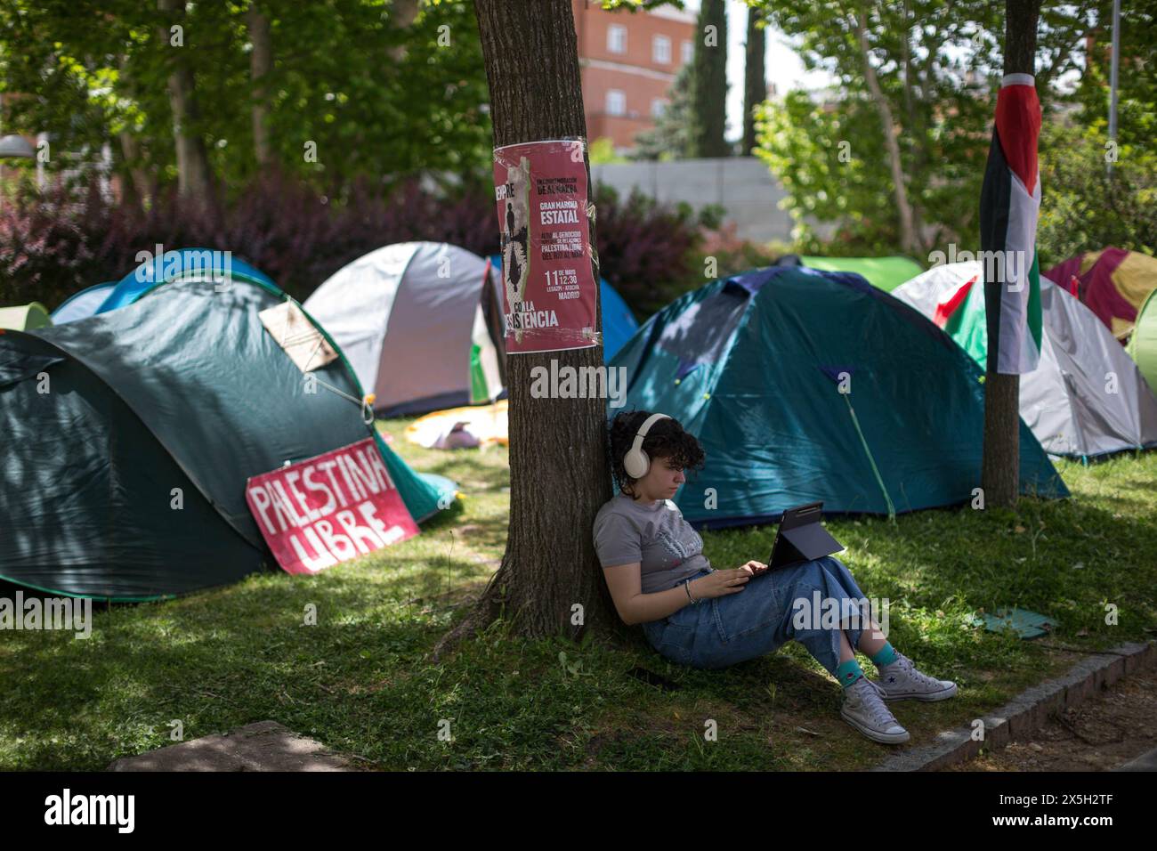 Madrid, Spagna. 9 maggio 2024. Una donna studia seduto sotto un albero, accanto alle tende, durante un campeggio studentesco nel campus dell'Università Complutense di Madrid, chiedendo che il genocidio contro il popolo palestinese cessi. Studenti di diverse facoltà dell'Università Complutense di Madrid (UCM) hanno istituito un campo a tempo indeterminato con l'obiettivo di mostrare il loro sostegno al popolo palestinese e chiedere la fine del genocidio nella Striscia di Gaza. (Foto di Luis Soto/SOPA Images/Sipa USA) credito: SIPA USA/Alamy Live News Foto Stock