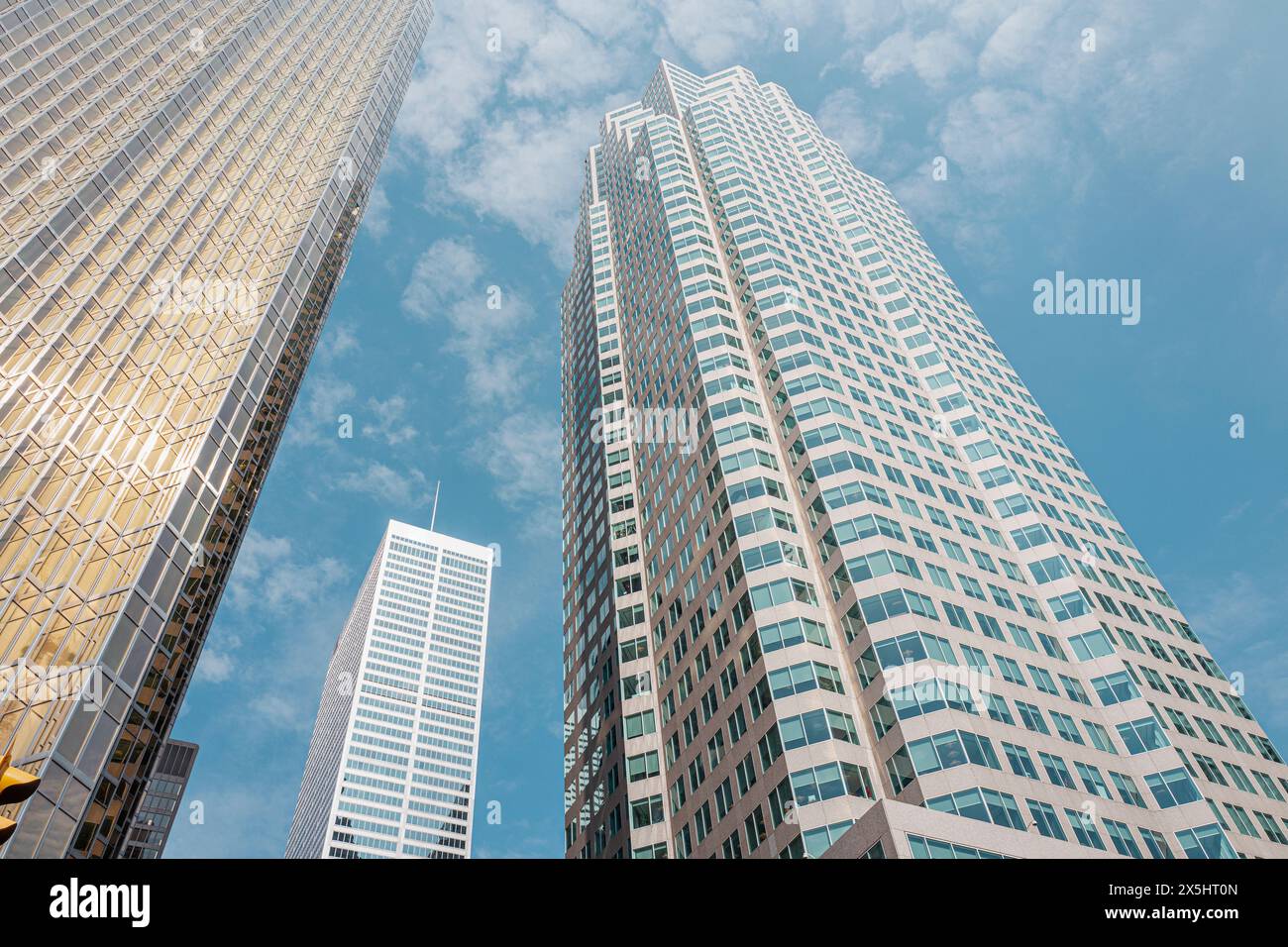 Vista dal basso del moderno ufficio dei grattacieli nel quartiere finanziario della città di Toronto, con un suggestivo cielo blu e morbide nuvole. Foto Stock