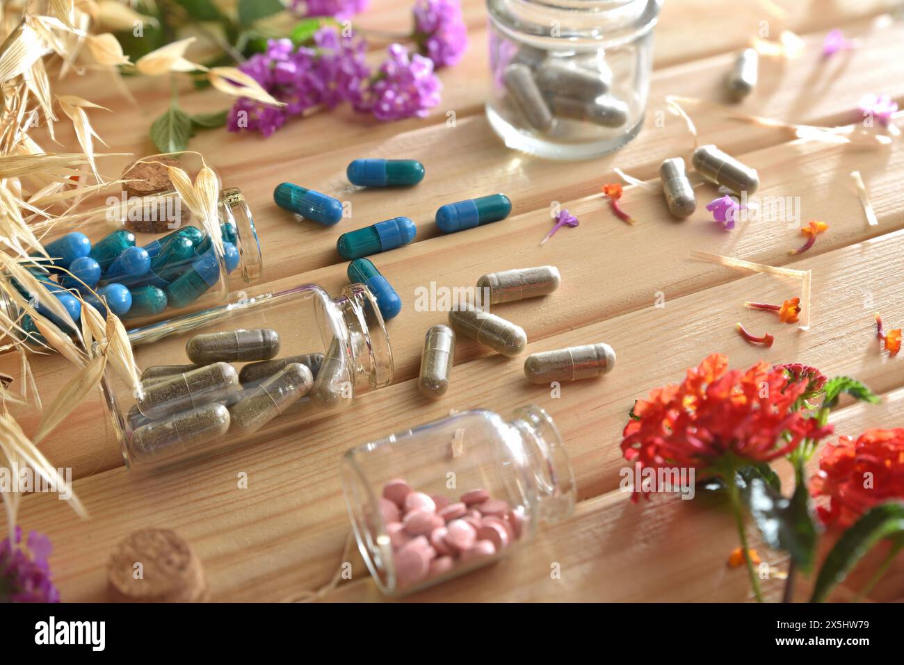 Medicinali naturali con piante e fiori su tavola di legno con capsule e pillole in vasetti di vetro. Vista rialzata. Foto Stock