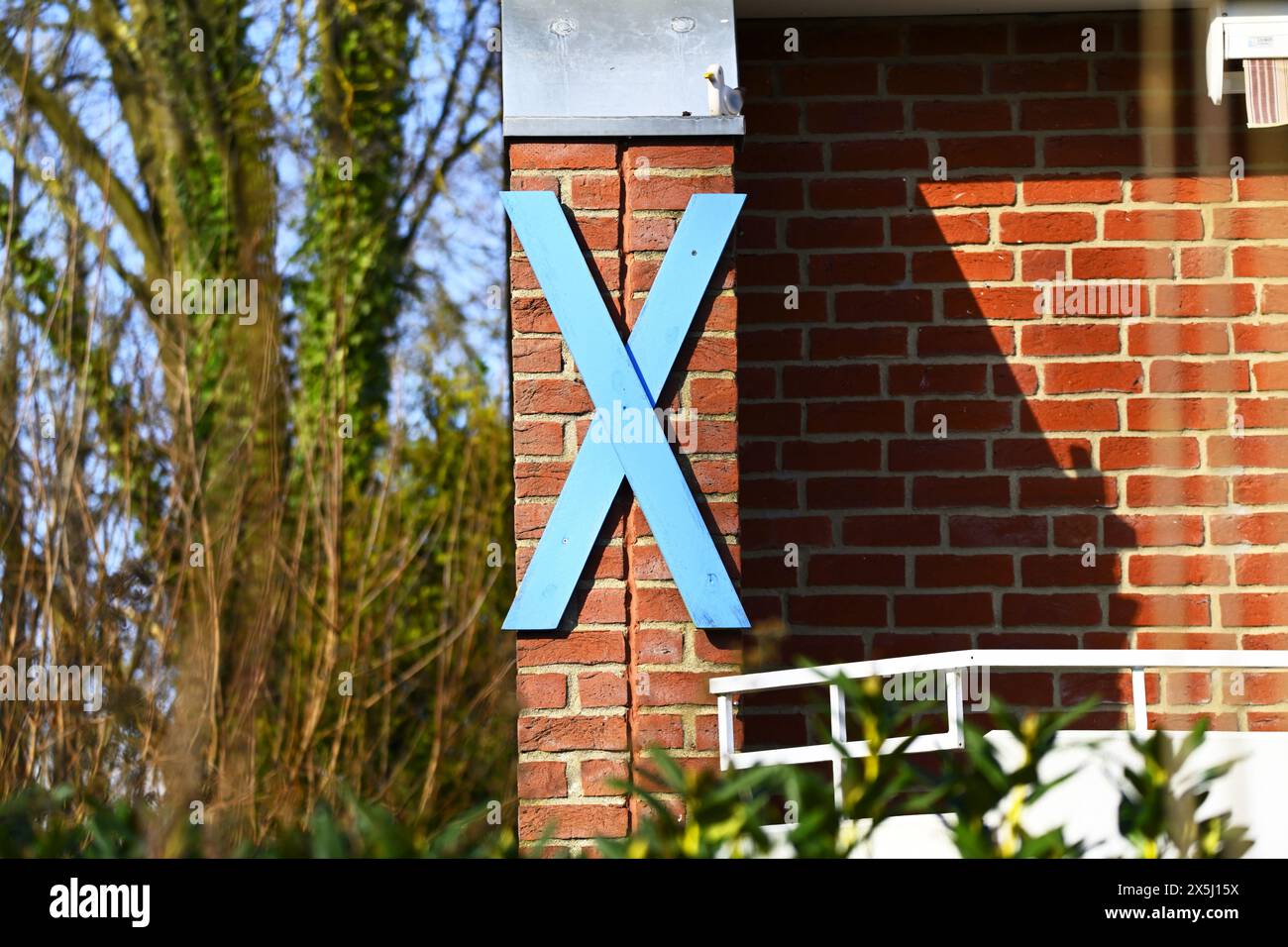 Blaues Holzkreuz als Protestzeichen gegen den Bau des Fehmarnbelttunnels an einem Haus in Haffkrug, Schleswig-Holstein, Deutschland Foto Stock
