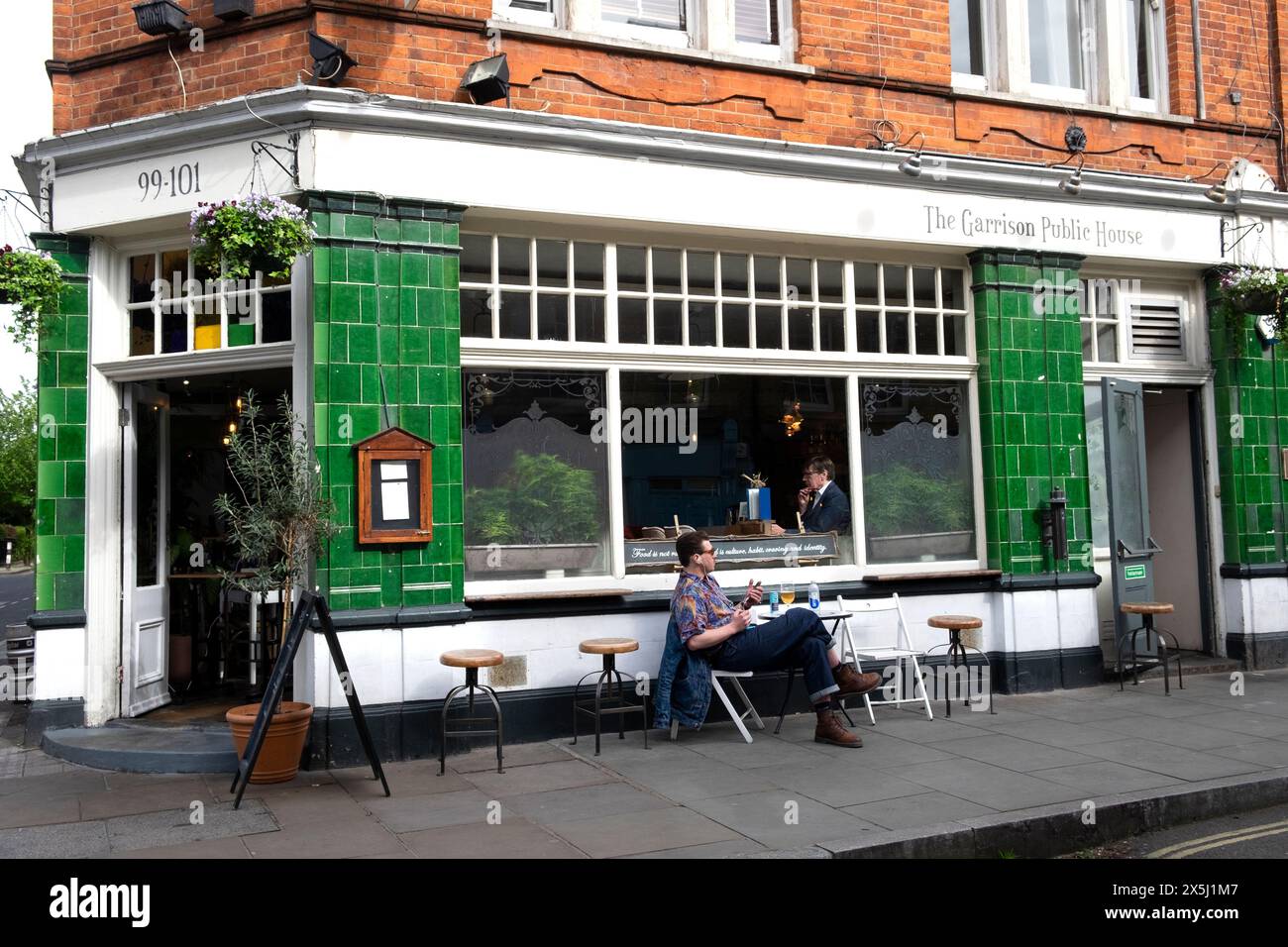 Uomo che siede al tavolo fuori dal pub Garrison in Bermondsey Street a Bermondsey South London Inghilterra Regno Unito KATHY DEWITT Foto Stock
