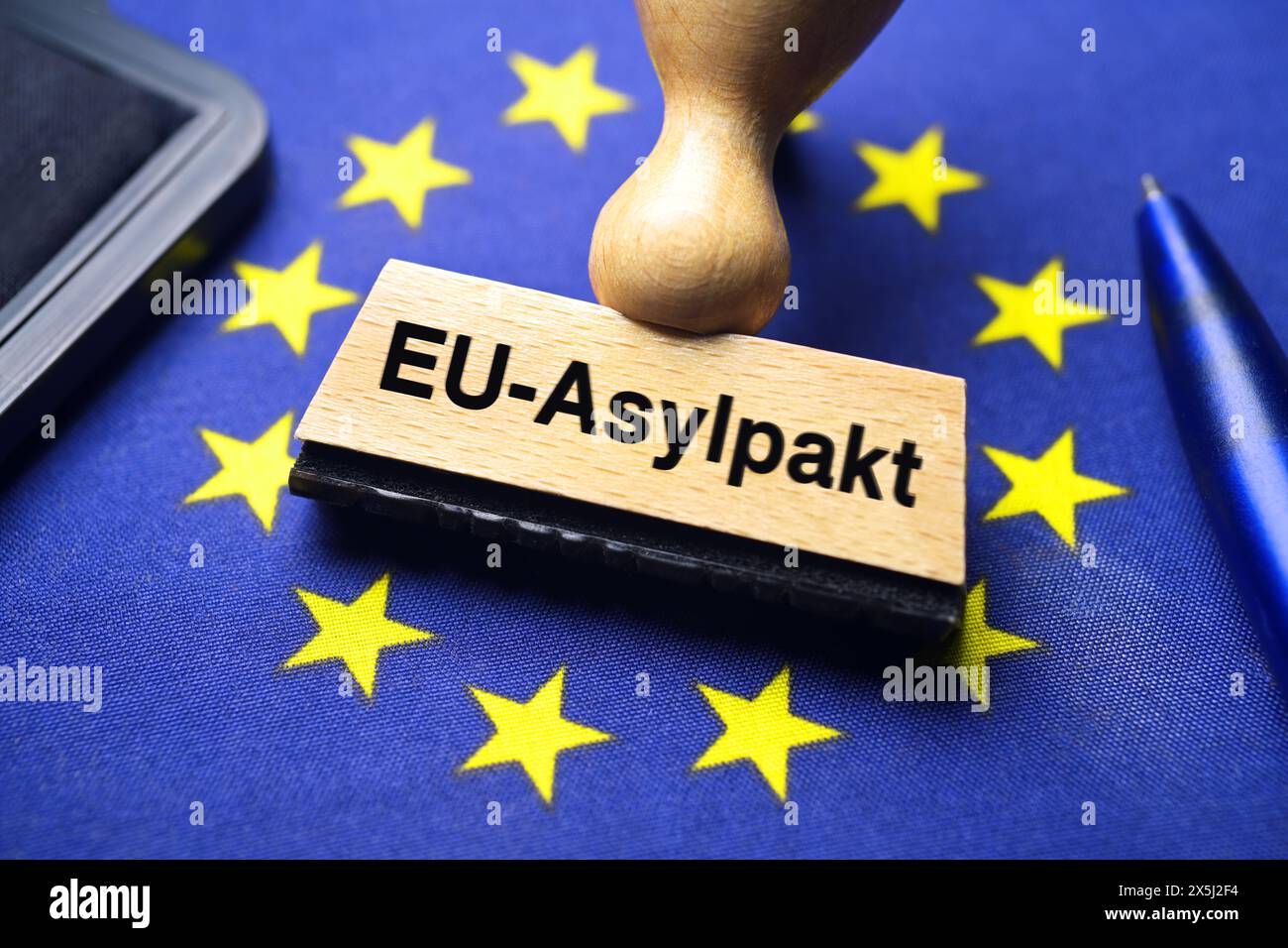 FOTOMONTAGE, Stempel mit Aufschrift EU-Asylpakt auf EU-Fahne Foto Stock