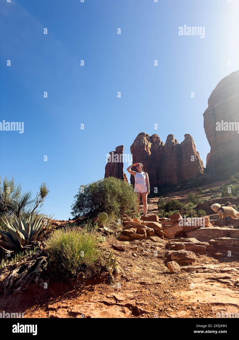 Donna escursionista che guarda il panorama mentre cammina sulle rocce rosse Foto Stock