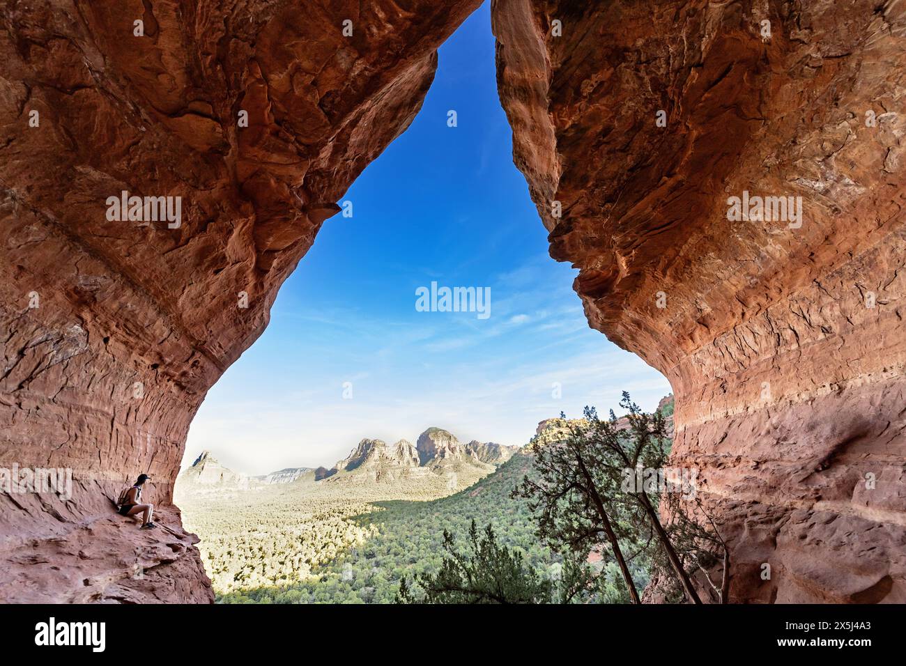 Vista dell'apertura della grotta che guarda al cielo e alle montagne Foto Stock