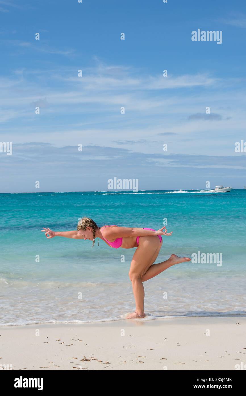 Una donna bionda fa yoga in bikini su una spiaggia dei Caribeei Foto Stock