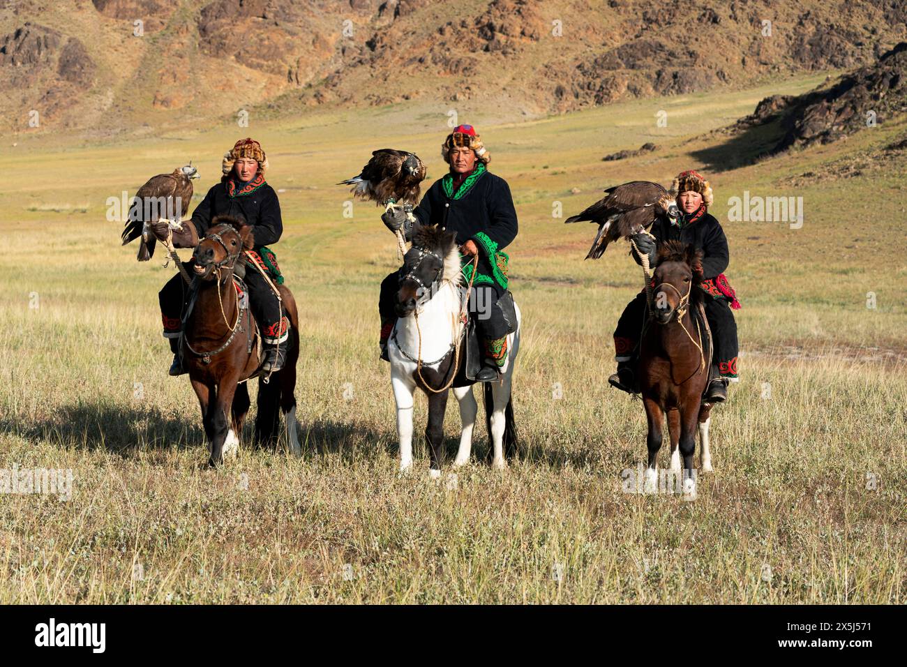 Asia, Mongolia, provincia di Bayan-Olgii. Altai Eagle Festival, kazako e i suoi due figli trasportano le loro aquile d'oro mentre sono a cavallo. (Solo per uso editoriale) Foto Stock