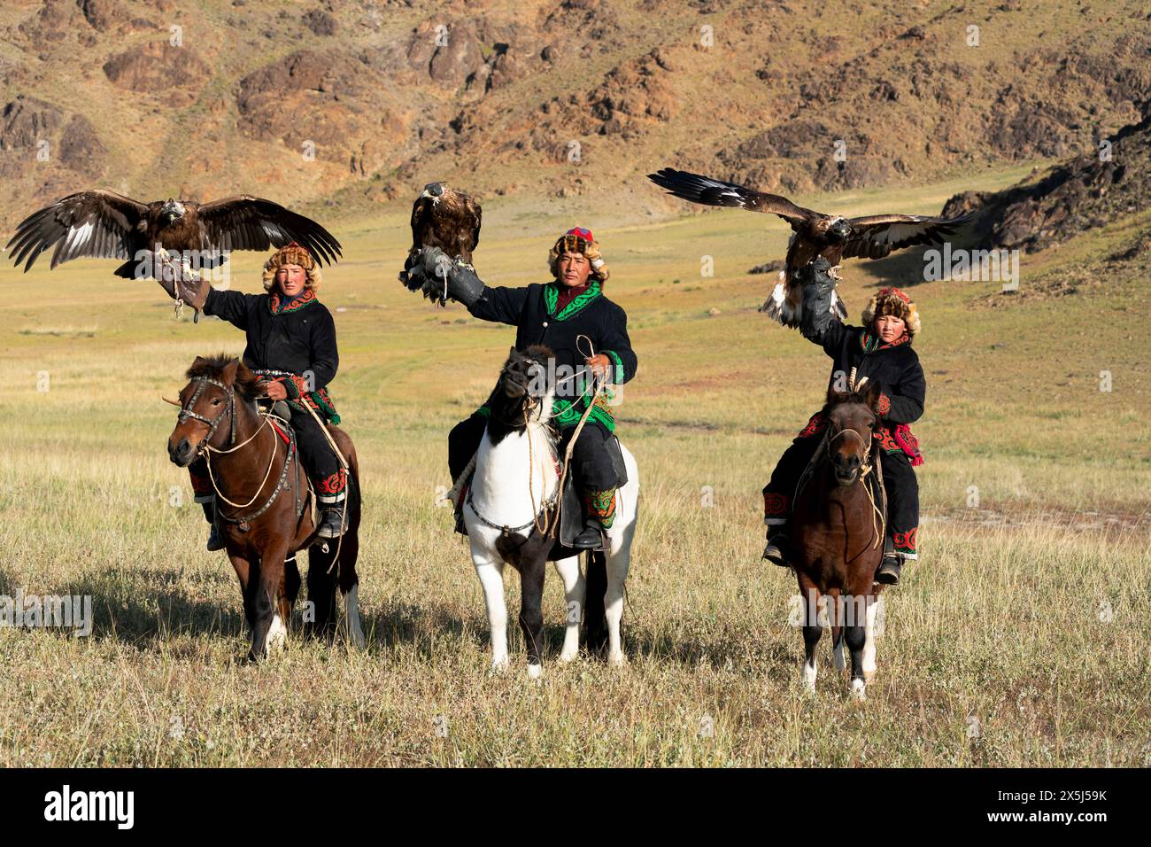 Asia, Mongolia, provincia di Bayan-Olgii. Altai Eagle Festival, kazako e i suoi due figli trasportano le loro aquile d'oro mentre sono a cavallo. (Solo per uso editoriale) Foto Stock